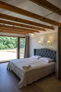 a bedroom with a large bed with a large window at Sodyba Pelėdų medus in Vainekoniai