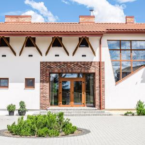 un edificio blanco con puerta de madera en Sodyba Pelėdų medus, en Vainekoniai