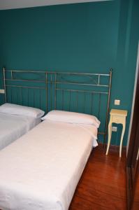 two beds in a room with a blue wall at Apartamentos de Turismo Rural Vinacua in Sos del Rey Católico