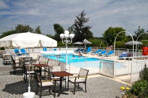 a pool with tables and chairs next to a swimming pool at La Villa des Longchamps Location du samedi au samedi in Saint-Jouan-des-Guérets