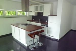 a kitchen with white cabinets and a bar stool at Rheinblick Résidence in Tägerwilen