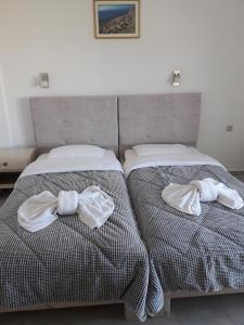 two beds with towels on them in a bedroom at Knossos Hotel in Kalamaki