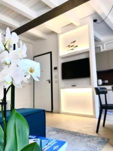 um vaso com flores brancas em uma sala com TV em 3 Amici al Teatro em Verona