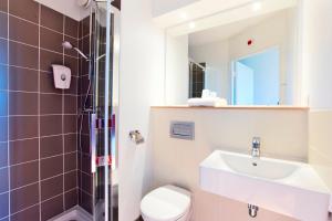un bagno con lavandino, water e specchio di Premiere Classe Caen Nord - Mémorial a Caen
