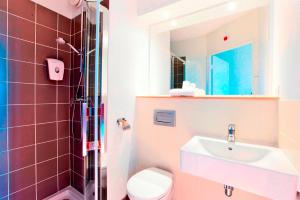 un bagno con lavandino, water e specchio di Premiere Classe Caen Nord - Mémorial a Caen