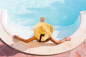 uma pessoa com um chapéu de palha sentada numa piscina em Fattoria di Collemezzano em Collemezzano
