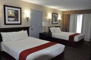 a hotel room with two beds and two windows at Ramada by Wyndham Abbotsford in Abbotsford