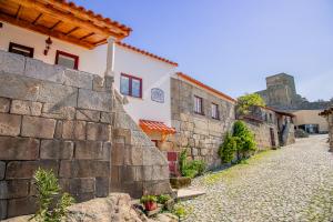 a street in a village with a stone wall at Casa do Leão in Marialva
