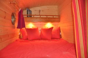 a bedroom with a red bed in a wooden room at Gite Insolite "La Roulotte des Elfes", Au Milieu de Nulle Part in Outines