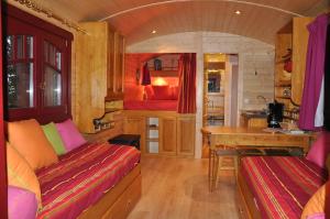 a room with a table and a kitchen in a train at Gite Insolite "La Roulotte des Elfes", Au Milieu de Nulle Part in Outines