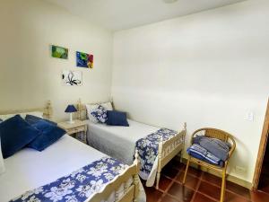 une chambre avec deux lits et une chaise dedans dans l'établissement Tranquilidade a alguns passos da praia - churrasqueira, super wi-fi!, à Matinhos
