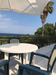una mesa y sillas blancas con sombrilla y el océano en Kessaris Apartments, en Chrani