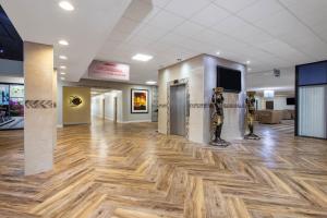 a lobby with a wooden floor and two men statues at Ramada by Wyndham Tampa Westshore Airport South in Tampa