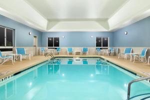 uma piscina com cadeiras e mesas num quarto em Holiday Inn Express & Suites - Spartanburg-North, an IHG Hotel em Spartanburg