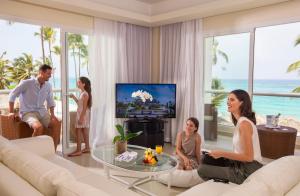 a family sitting in a living room watching a tv at Royalton Punta Cana, An Autograph Collection All-Inclusive Resort & Casino in Punta Cana
