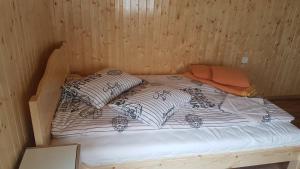 a bed in a wooden room with two pillows at Casa La LEPE in Roşia Montană