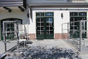 d'une terrasse avec des portes vertes, une table et des chaises. dans l'établissement Strandhotel Dennenbos, à Oostkapelle