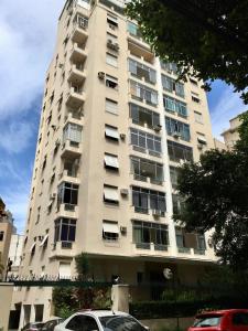 wysoki budynek z samochodami zaparkowanymi przed nim w obiekcie São Salvador, Flamengo, 3 quartos w mieście Rio de Janeiro
