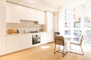 cocina con armarios blancos, mesa y sillas en Casa da Suite Perfecta en Milán