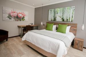 a bedroom with a large bed with green pillows at Vinique Guesthouse in Nelspruit