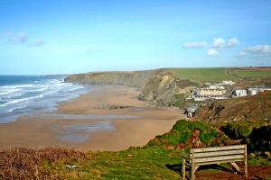 a bench sitting on a hill overlooking a beach at Tregurrian Villas in Newquay