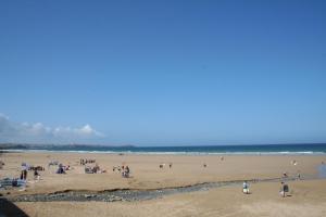 a group of people on a beach near the ocean at Tregurrian Villas in Newquay