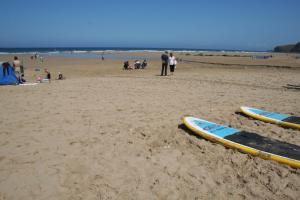 a group of people on a beach with surfboards in the sand at Tregurrian Villas in Newquay