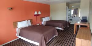 2 camas en una habitación de hotel con paredes de color naranja en Mission Inn en San Antonio