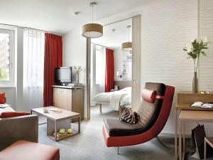 a living room with a bed and a red chair at Aparthotel Adagio Basel City in Basel