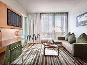 a living room with a couch and a tv at Novotel Auckland Airport in Auckland