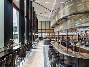 a restaurant with a bar with chairs and tables at Novotel Auckland Airport in Auckland