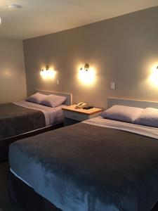 a hotel room with two beds and a desk at Ranchland Villa Motel in Merritt
