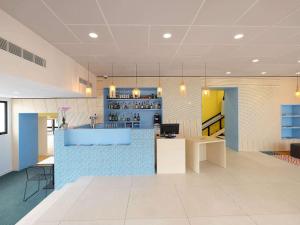 a lobby with a blue counter and a bar at Hôtel ibis Styles Auxerre Nord in Auxerre