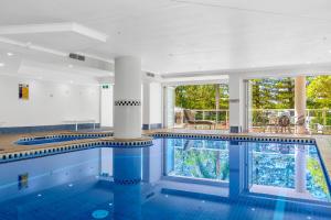 uma piscina com piso de azulejo azul e colunas em Oscar On Main Beach Resort em Gold Coast