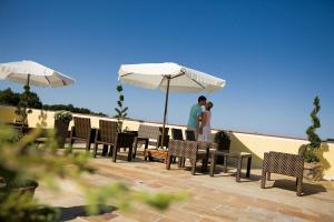 zwei Personen stehen auf einer Terrasse unter einem Sonnenschirm in der Unterkunft Hotel Panoramahof Loipersdorf in Jennersdorf