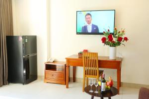 een woonkamer met een tafel en een televisie aan de muur bij Son Tra Green Hotel & Apartment in Da Nang