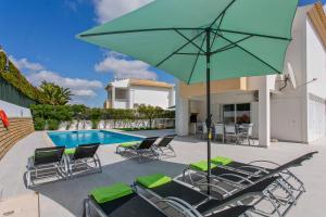 a patio with chairs and an umbrella and a pool at Villas Mar e Brisa in Albufeira