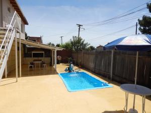 a backyard with a swimming pool and an umbrella at El Galpon in Valeria del Mar