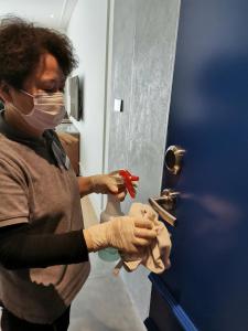 a woman wearing a mask and gloves opens a door at Barony Park Hotel Shanghai in Shanghai