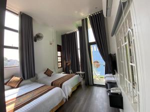 Habitación de hotel con 2 camas y ventanas grandes. en CENTRAL HOME en Pleiku