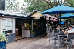 a restaurant with people sitting at a table with an umbrella at Nomads Noosa in Noosa Heads