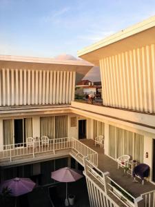 un balcón de un hotel con mesas y sombrillas en Pom Pom's Bali Apartments, en Kerobokan