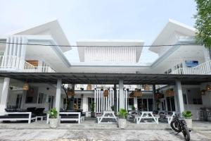 a building with a patio with white tables and chairs at Pom Pom's Bali Apartments in Kerobokan