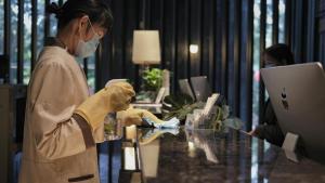 a woman in a mask working at a desk with a computer at Paco Hotel Tianpingjia Metro Guangzhou - Canton Fair free shuttle bus in Guangzhou