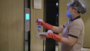una mujer con una máscara y guantes y una puerta en Paco Hotel Tianpingjia Metro Guangzhou - Canton Fair free shuttle bus, en Guangzhou