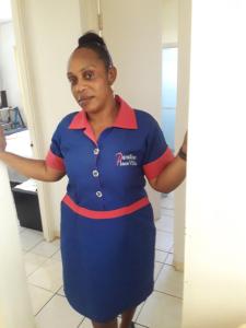 a woman standing in a kitchen wearing a blue uniform at Paradise Place Grande in Cave Hill
