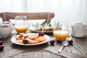 una mesa con un plato de comida y vasos de zumo de naranja en Hotel / Pension Villa Tanahlot, en Zandvoort