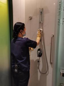 a woman in a mask is washing a shower stall at Hampton by Hilton Guangzhou Tianhe Sports Center in Guangzhou