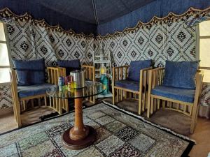 ein Wohnzimmer mit einem Tisch, Stühlen und einer Wand in der Unterkunft Alsarmadi Desert Camp in Shāhiq