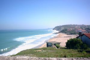 a view of a beach with a house and the ocean at LOCBASQUE COM Appartement Résid Bidart Plage , classé meublé de tourisme 3 étoiles in Bidart